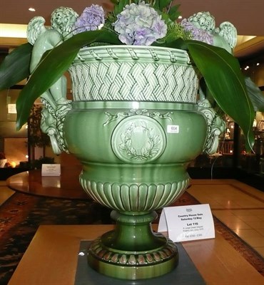 Lot 604 - A large green glazed pottery urn, circa 1870, the basket weave and reeded neck flanked by two putti