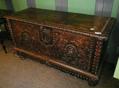 Lot 835 - A Continental chestnut coffer, the rectangular lid deeply chip carved and with foliate carved edge