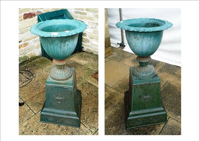 Lot 1155 - Pair of cast iron garden urns on plinth bases