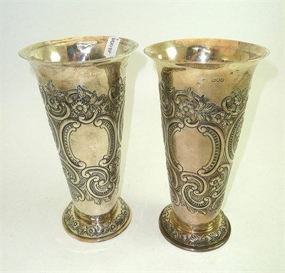 Lot 76 - A pair of silver vases, each with all over repoussé decoration