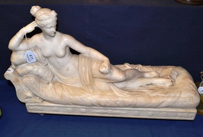 Lot 411 - A carved alabaster model of a reclining classical woman (a.f.)