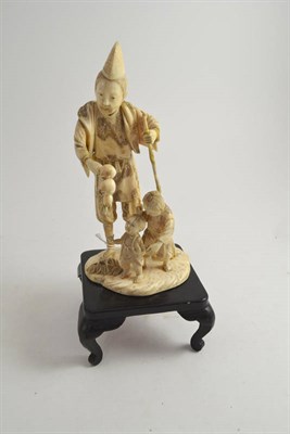 Lot 555 - A Japanese carved ivory figure group, Meiji period (1868-1912), as a man in a pointed hat...