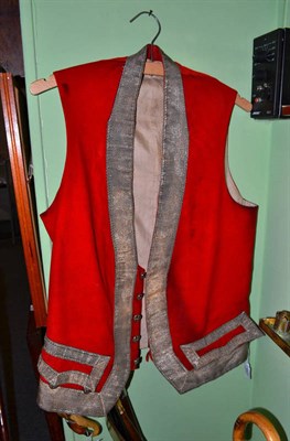 Lot 601 - 19th century red wool livery waistcoat with a woven white metal applique trim, cotton lining,...