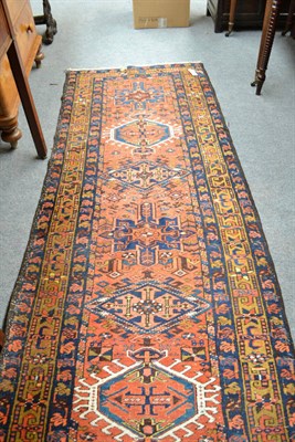 Lot 743 - A narrow Heriz runner, Persian Azerbaijan, The terracotta field with a single row of medallions...