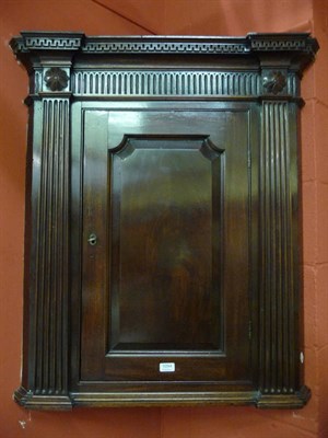 Lot 1094 - A Georgian mahogany corner cupboard with dentil cornice