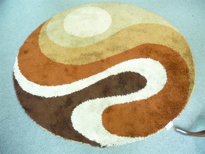 Lot 1099 - A 1970's French abstract circular wool rug, in orange, brown and cream, unmarked, 195cm