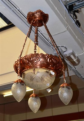 Lot 1110 - An Arts & Crafts copper light fitting with cut glass dome and three suspended pendants