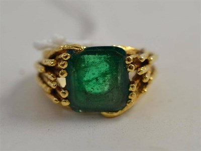 Lot 136 - An emerald ring, the step-cut emerald in a textured branched shoulder shank, finger size M