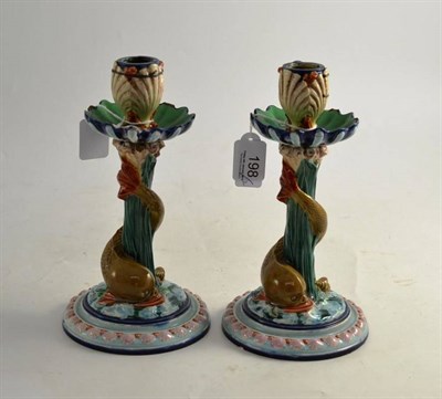 Lot 198 - A pair of Royal Worcester Majolica candlesticks with stylised dolphins and shell motifs