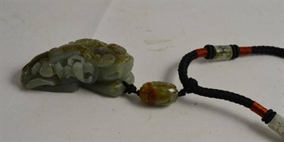 Lot 262 - A Chinese carved jade/jadeite fo dog pendant on woven neck cord