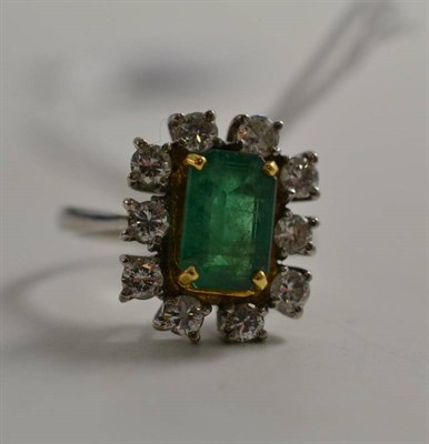 Lot 306 - An 18ct gold emerald and diamond cluster ring, the step cut emerald in a yellow corner claw setting