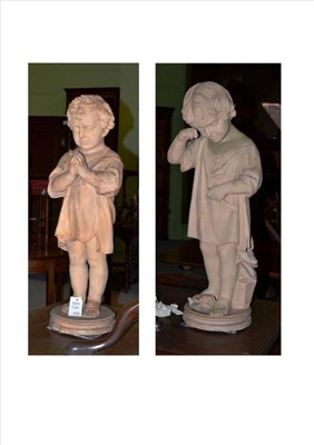 Lot 450 - A pair of terracotta figures of children, late 19th century, each standing wearing loose...