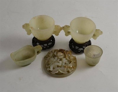 Lot 493 - A soapstone carved plaque and pair of moulded green glass bowls on hardwood stands, a Jade type...