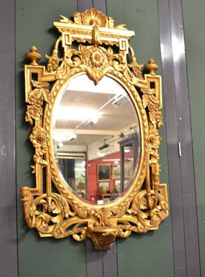 Lot 935 - An ornate giltwood and gesso wall mirror with candle sconces and bevelled oval plate