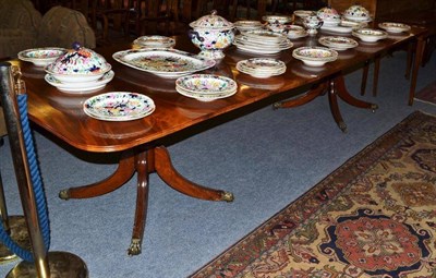 Lot 1055 - A mahogany twin pedestal dining table raised on turned column supports, brass paw feet and castors