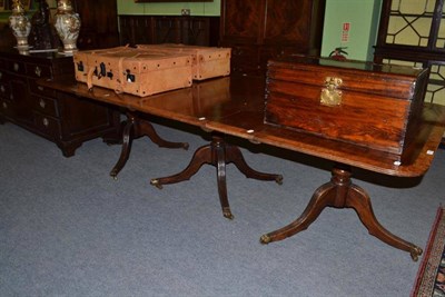 Lot 1154 - A George IV style mahogany and yew banded triple pillar dining table