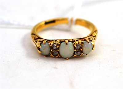 Lot 128 - An Opal and Diamond Ring, three cabochon opals spaced by pairs of diamonds, in a yellow claw carved