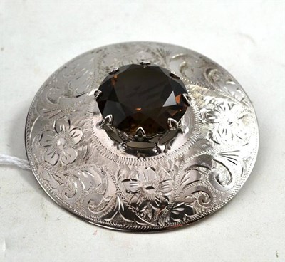 Lot 566 - A Silver Smokey Quartz Brooch, the disk engraved with floral motifs and inset centrally with a...