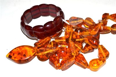 Lot 567 - An Amber Bracelet, of cherry red panels on elastic, and A Necklace, of drop shaped forms (2)