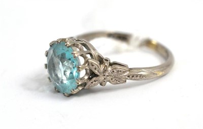 Lot 415 - A light blue paste ring, simulating aquamarine, in a decorative mid 20th century setting,...