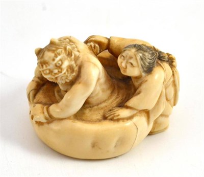 Lot 611 - A Japanese carved elephant ivory netsuke, late Meiji period (1868-1912), as a woman scrubbing...