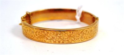 Lot 681 - A 9ct gold half engraved hinged bangle