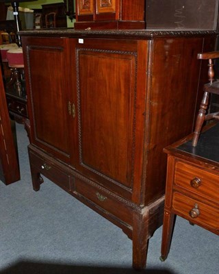 Lot 821 - George III mahogany dwarf linen press with cupboard doors sliding trays and raised on a stand,...