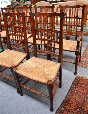 Lot 876 - A set of ten stained beech rush-seated dining chairs, 20th century, with triple spindle back...