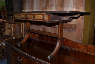 Lot 942 - A reproduction walnut coffee table on brass paw feet, 111cm extended