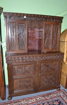 Lot 953 - Carved oak cupboard with central shutter roller door, width 129cm