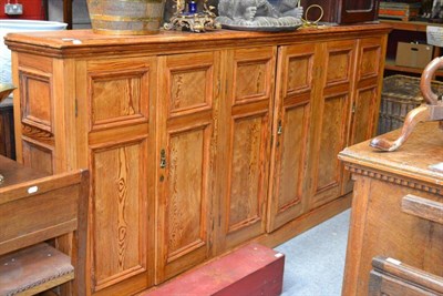 Lot 1437 - A large pitch pine standing cupboard with three pairs of doors enclosing a shelved interior, length