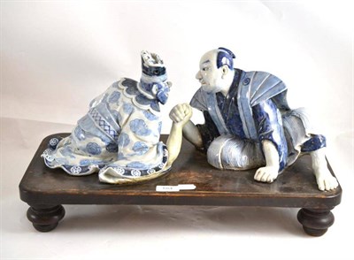 Lot 184 - An Arita porcelain figure group, in 17th century style, as a man and an oni arm wrestling, both...