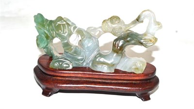 Lot 274 - A jadeite carving of a gnarled pine tree and rockwork on fitted wood stand