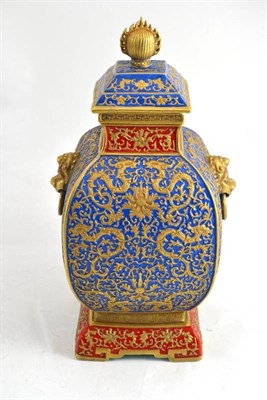 Lot 318 - A Chinese porcelain vase and cover, carved with dragons and lotus, in red and blue glazes and gilt