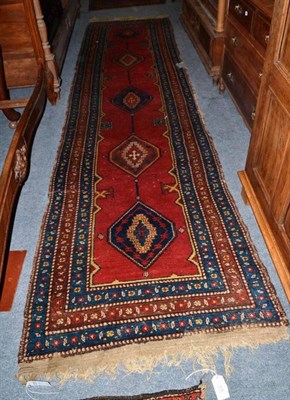 Lot 473 - Narrow North West Persian runner, the plain madder field with a column of polychrome hexagons...