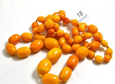 Lot 18 - An amber bead necklace, 58 beads of opaque orangey-yellow colour, length 102cm