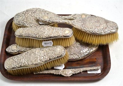 Lot 114 - A silver basket three piece dressing table set, two repousse with covers, two similar brushes and a