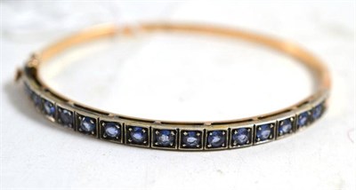 Lot 246 - A sapphire line bangle, stamped '585'