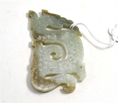 Lot 580 - A Chinese celadon jade plaque, of archaic form, worked as a scrolling dragon with boss motifs, 10cm