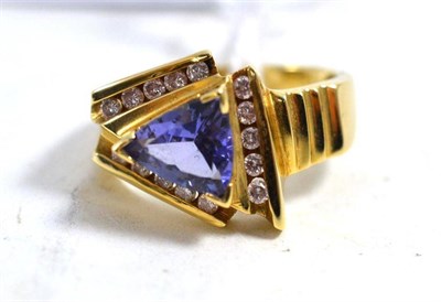 Lot 608 - A contemporary tanzanite and diamond cluster ring, a trilliant cut tanzanite in yellow claw...