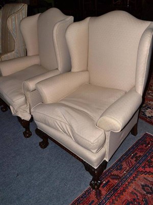 Lot 780 - A pair of cream upholstered wing armchairs with ball and claw feet