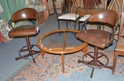 Lot 1316 - A pair of tubular chrome tub shaped swivel chairs and a G-plan style glass topped coffee table