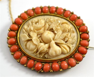 Lot 34 - A Victorian ivory brooch finely carved with flowers and fruit within a coral border