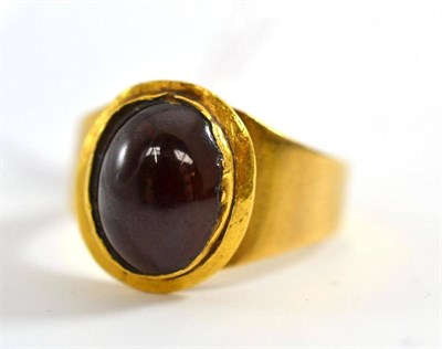 Lot 36 - # A garnet ring, the cabochon garnet in a yellow collet setting, to a tapered shank, finger size Q
