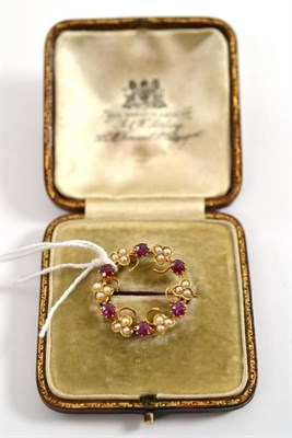 Lot 39 - A ruby and split pearl hoop brooch, trios of split pearls alternate with round cut rubies, measures