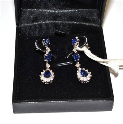 Lot 209 - A pair of sapphire and diamond drop earrings, two pear cut sapphires alternate with two round...