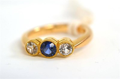 Lot 247 - A synthetic sapphire and white stone ring, the round brilliant cut sapphire flanked by a round...