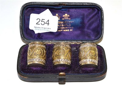 Lot 254 - # A set of white metal and parcel gilt cylindrical pepperettes with cast scrolled decoration in...