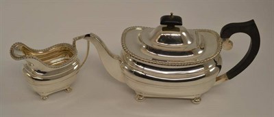 Lot 274 - A George V silver teapot and cover, 31cm long; and matching milk jug with gadroon borders