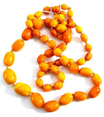 Lot 431 - An amber bead necklace, 58 beads of opaque orangey-yellow colour, length 102cm